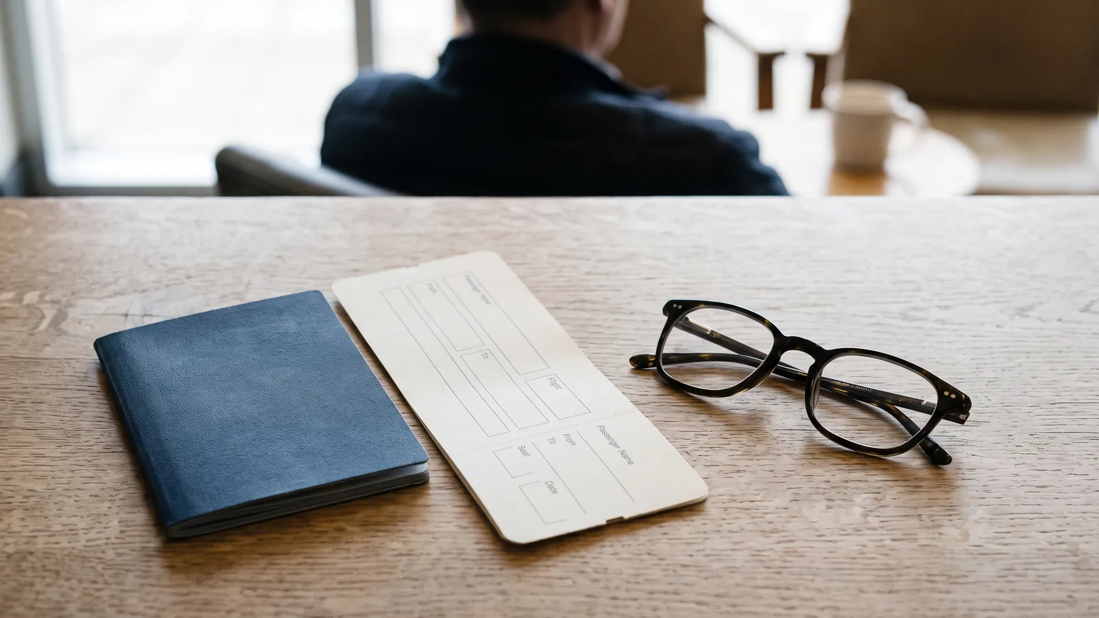 A passport and a boarding pass on a desk next to a pair of glasses